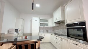 Eine Küche mit weißen Schränken, einer Mikrowelle, einer Glasinsel und einem Backofen.