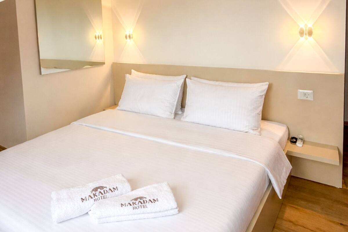 A hotel room with a bed, pillows, a nightstand, and a towel with the hotel name.