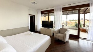 Ein Hotelzimmer mit zwei Betten, einem Fernseher, einem Sofa und einem Balkon mit Blick.