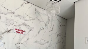 A marble reception desk with a black marble base, a glass top, and a hanging crystal chandelier. - Hotel Santa Rita (Amarante do Maranhão)