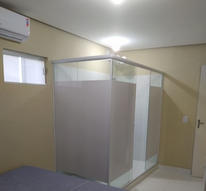 A room with a bed, a wardrobe, a window, and an air conditioning unit.