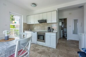 A modern kitchen with white cabinets, a built-in oven, and a coffee maker. - Apartment close to the beach with balcony and sea view (Dramalj)