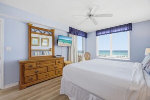 A bedroom with a bed, dresser, TV, ceiling fan, and a window with a view of the beach. - Large 3 Bedroom Beachfront Condo - Sleeps 10! Free Seasonal Beach Service! (Fort Walton Beach)