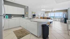 Una cocina moderna con armarios blancos, una isla central y una zona de comedor con sillas.