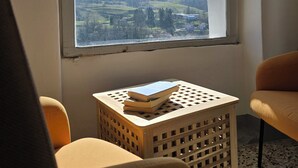 A room with a large arched window, a small wooden table with books, and two chairs. - Ancient hermitage in the upper Langa. Experience the essence of a frontier land (Costa)