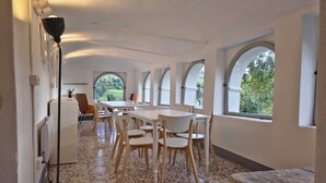 A spacious room with a long table and chairs, large arched windows, and a radiator. - Ancient hermitage in the upper Langa. Experience the essence of a frontier land (Costa)