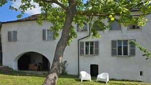 A white building with a tree in the foreground, two white chairs, and a small archway leading to an interior space. - Ancient hermitage in the upper Langa. Experience the essence of a frontier land (Costa)