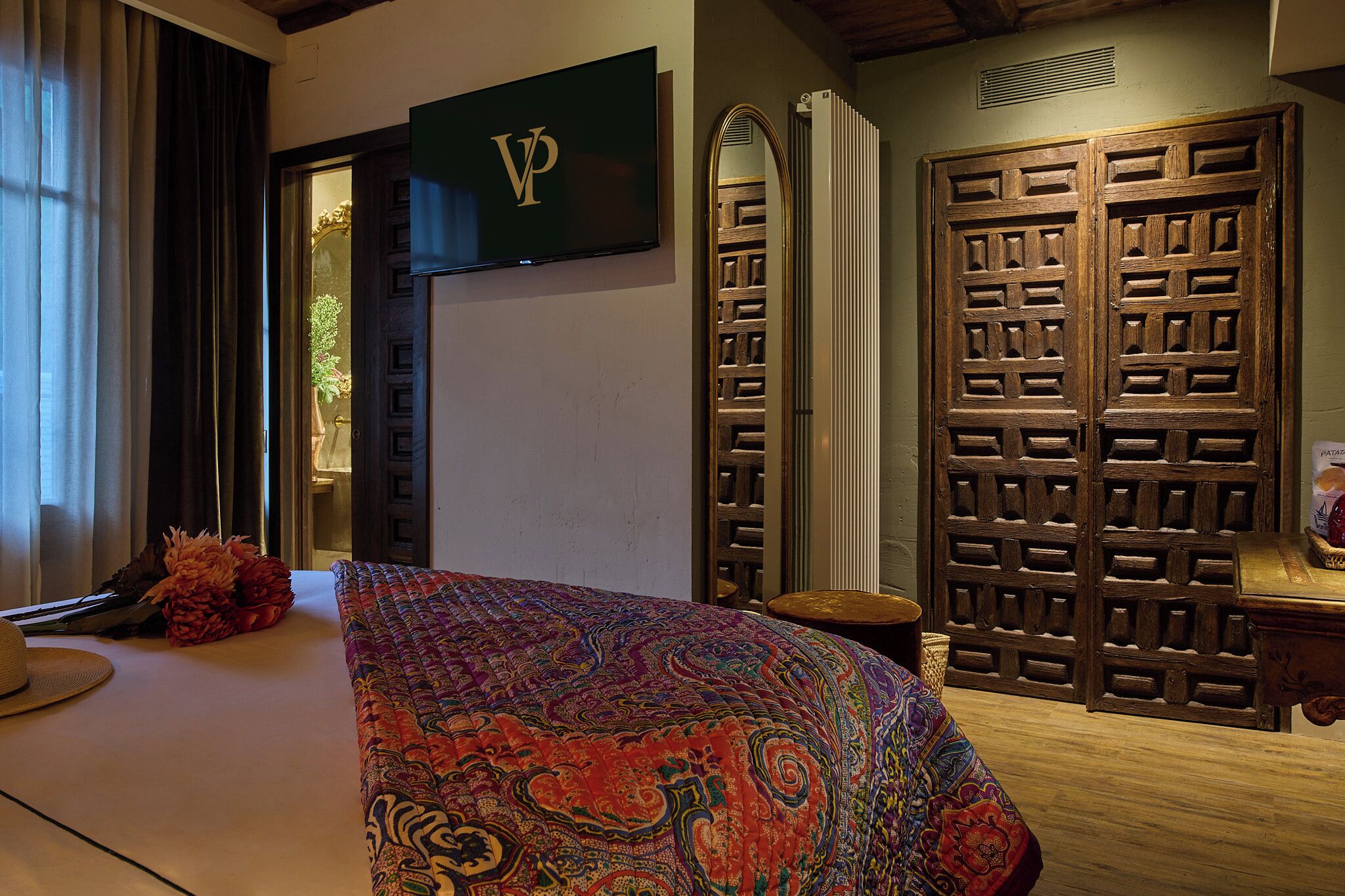A hotel room with a bed, a TV, a wardrobe, and a mirror.