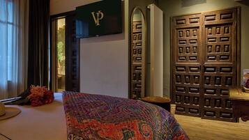 A hotel room with a bed, a TV, a wardrobe, and a mirror.