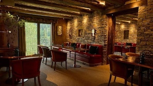 A rustic interior with stone walls, wooden furniture, and a large window providing a view. - Hotel Valle de Pineta (Bielsa)
