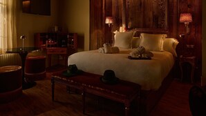 A cozy hotel room with a large bed, wooden paneling, a television, a desk, and a lamp. - Hotel Valle de Pineta (Bielsa)
