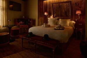 Una habitación de hotel acogedora con una cama grande, paneles de madera, televisor, escritorio y lámpara.