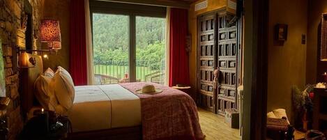 Een slaapkamer met een bed, een raam, een boekenplank en een deur naar een andere kamer.