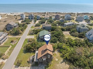 An aerial view of a coastal residential area with houses, a road, and a beach. - Just Beachy: Short walk to Beach | Hot Tub (Waves)