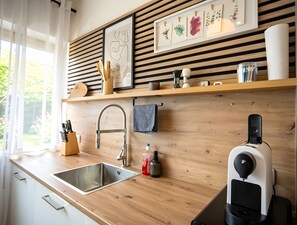Ett modernt kök med en diskho i rostfritt stål, en bänkskiva i trä och en kaffemaskin.