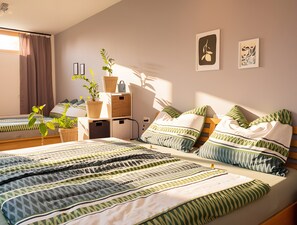 Quarto com duas camas, mesa de cabeceira, luminária e decoração na parede.