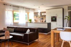 Un espacio habitable moderno con sofá, mesa de comedor y zona de cocina.