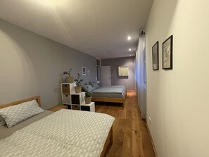 Une chambre avec deux lits, une table de chevet, un miroir et une étagère avec des plantes.
