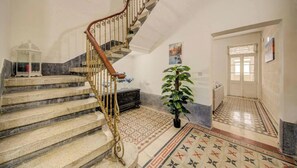 A staircase with ornate metal railings, a patterned floor, and a potted plant. - Private Room with Shared Kitchen in Hamrun Malta (Hamrun)