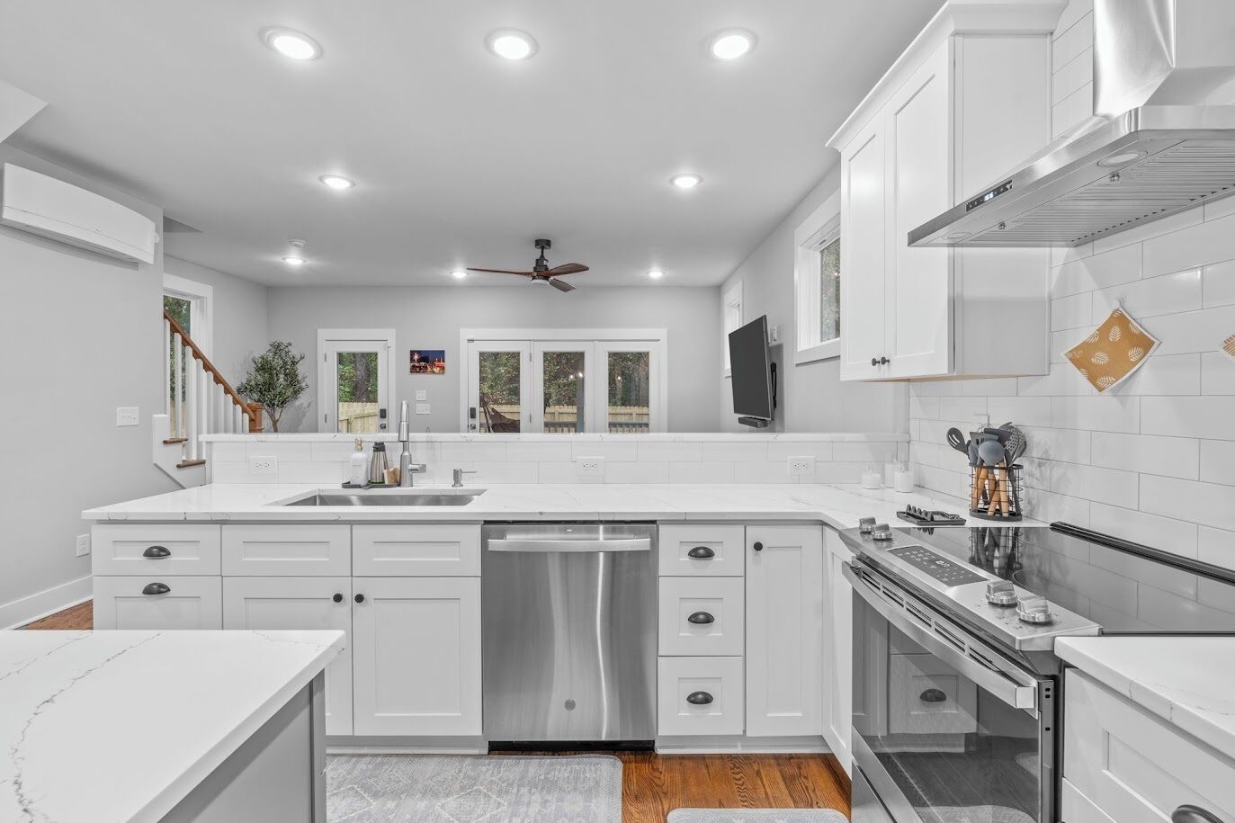 A modern kitchen with white cabinetry, a stainless steel dishwasher, and a built-in oven.