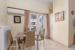 Ein Essbereich mit Tisch und Stühlen, einem Heizkörper, einem gerahmten Bild und einer Glastür, die auf einen Balkon im Freien führt.