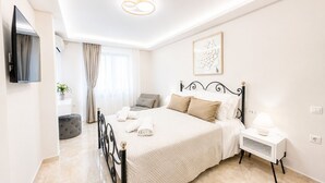 Ein Schlafzimmer mit Bett, Nachttisch, Lampe und einem an der Wand montierten Fernseher.