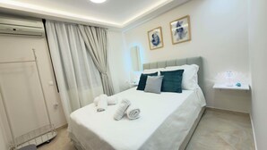 Ein Hotelzimmer mit einem Bett, einem Nachttisch mit Lampe, einem Wandspiegel und einer Tür mit Vorhängen.