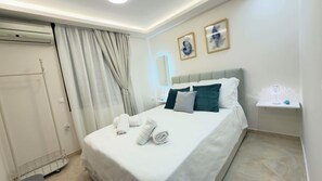 Ein Hotelzimmer mit einem Bett, einem Nachttisch mit Lampe, einem Wandspiegel und einer Tür mit Vorhängen.