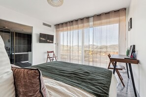 Ein modernes Schlafzimmer mit einem großen Bett, einem Schreibtisch und Blick auf die Stadt.