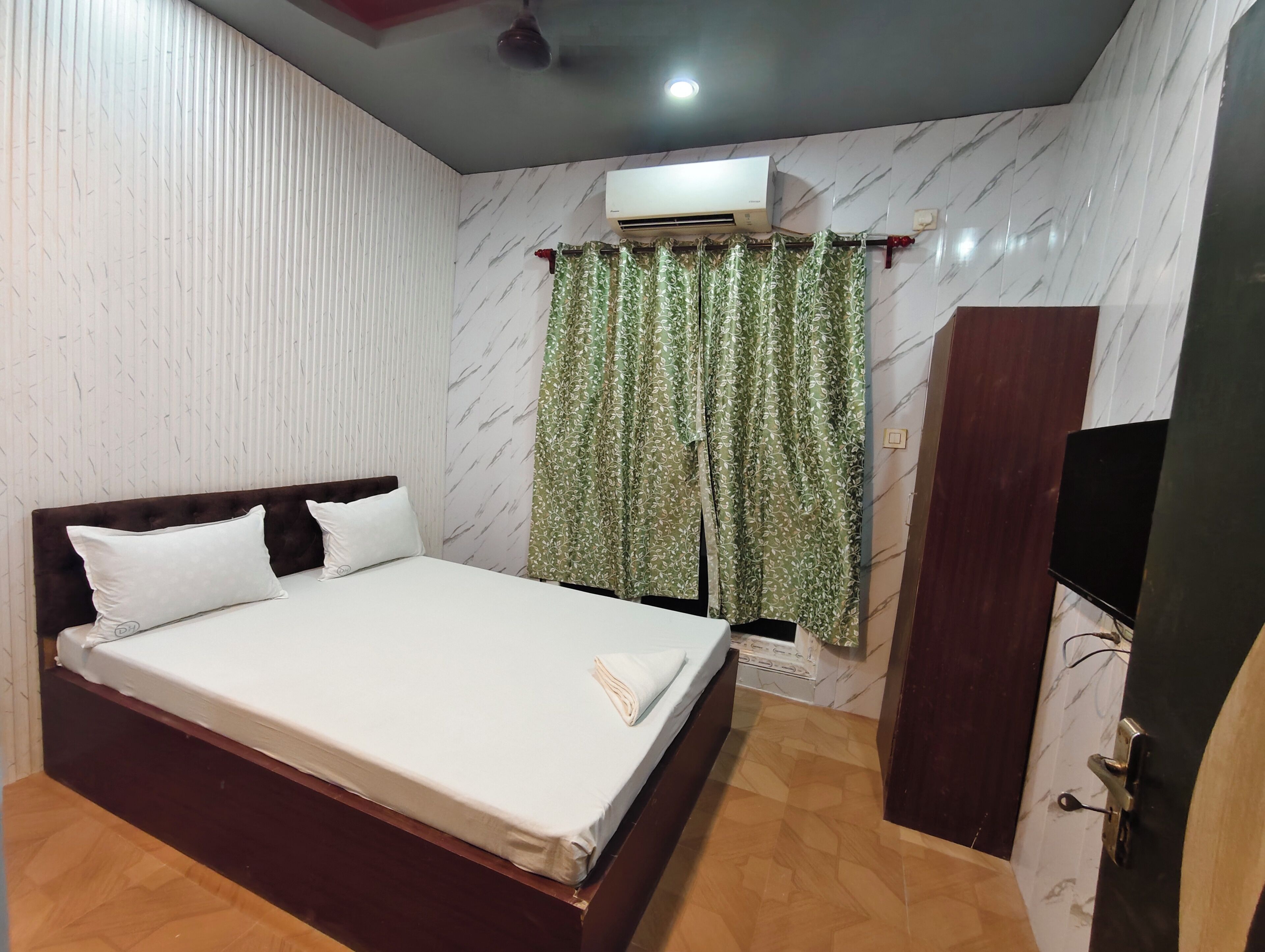 Une chambre à coucher comprenant un lit, une armoire, un climatiseur et un ventilateur de plafond.