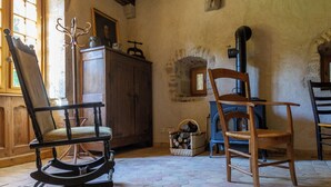 Una habitación con una mecedora de madera, una silla de madera, una chimenea y un armario.