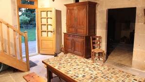 Una habitación con un armario de madera, una mesa con cubierta estampada, una silla y una escalera.