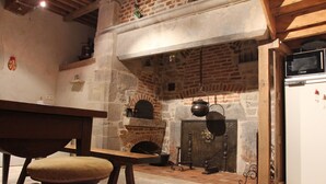 Una cocina rústica con chimenea de ladrillo, muebles de madera y un refrigerador blanco.