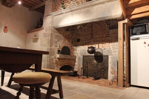 A rustic kitchen with a brick fireplace, wooden furniture, and a white refrigerator. - Gite in the heart of a former priory - quiet, leafy setting (Ruffey-sur-Seille)