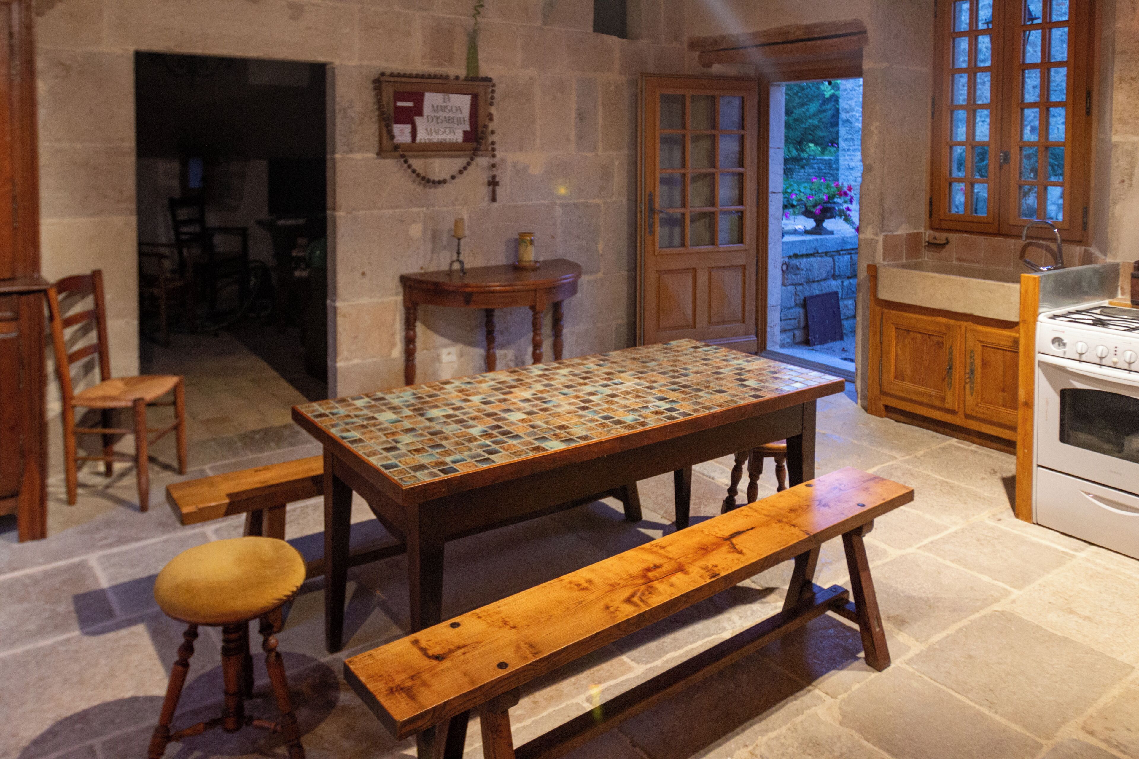Una cocina tradicional con una mesa de madera, un banco y una estufa.