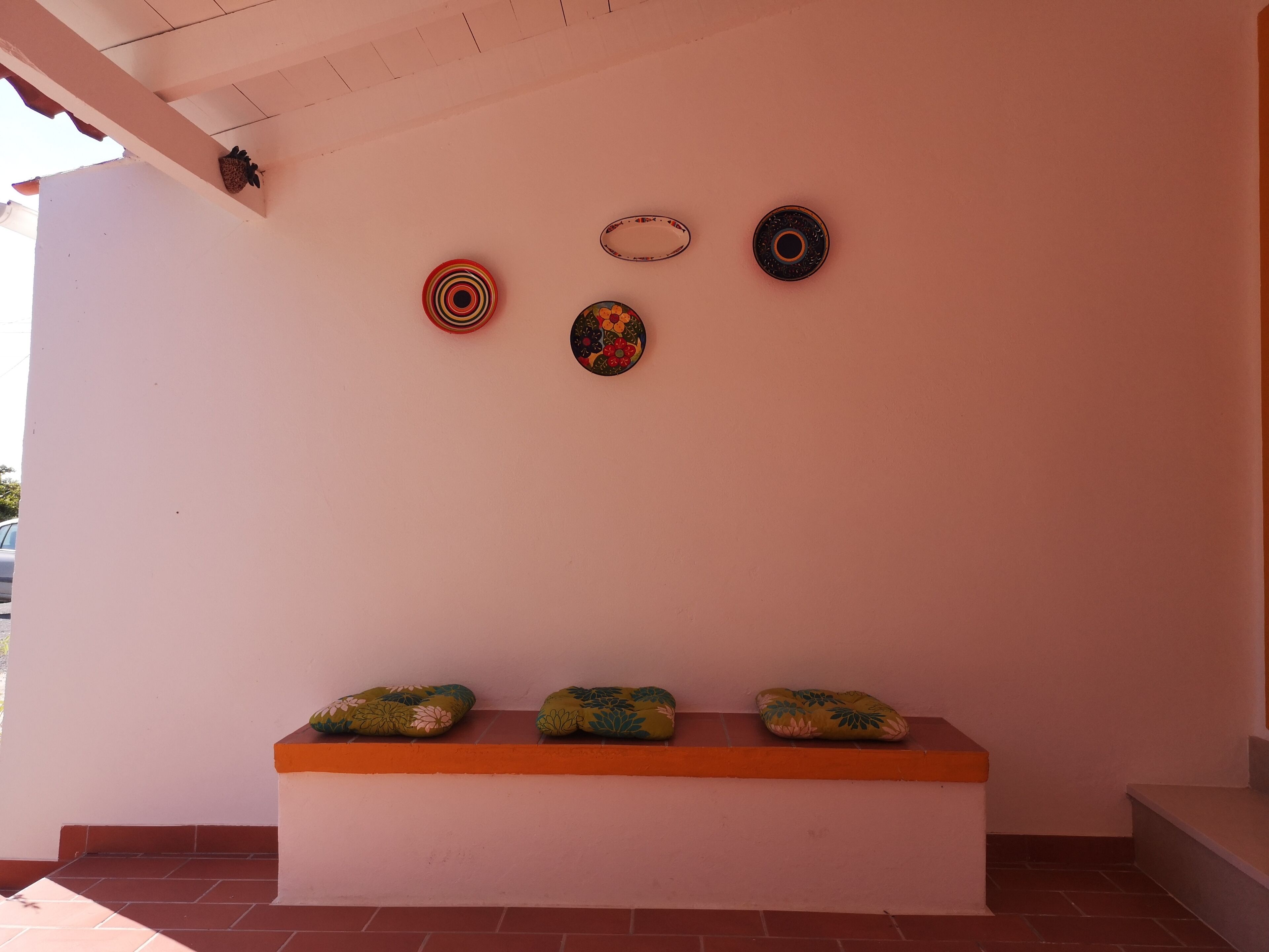 Una pared decorada con tres placas y un banco con cojines.