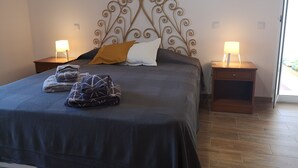 Ein ordentlich bezogenes Bett mit einem dekorativen Kopfteil, zwei Nachttischlampen und einem Fenster mit Blick.