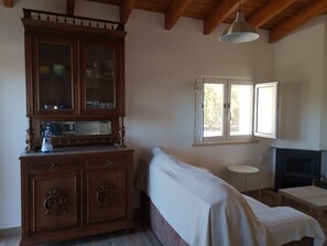 Una habitación con un armario de madera, una cama, una mesita, un televisor y una ventana con vista a árboles.