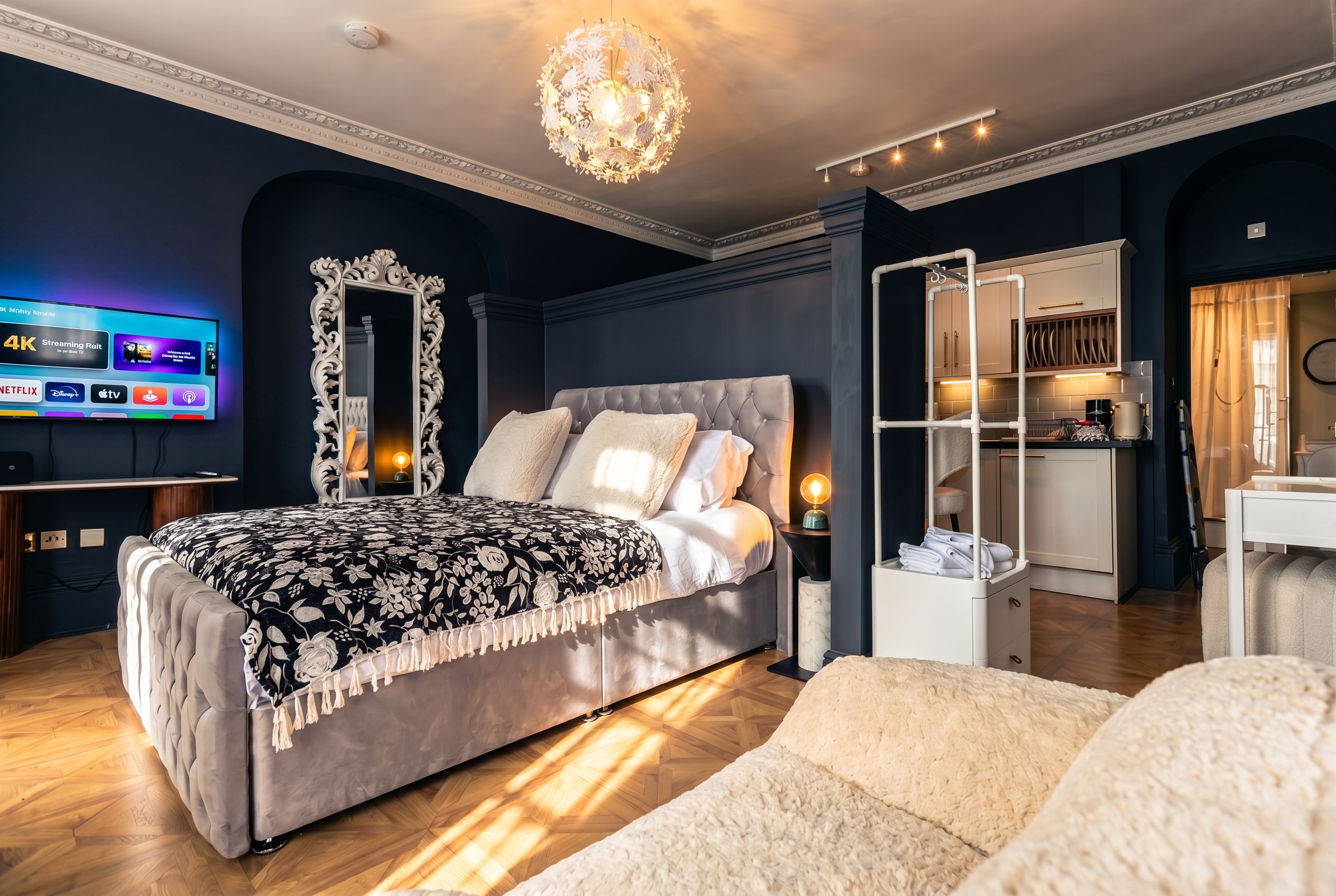 A modern bedroom with a large bed, a TV, a decorative mirror, and a built-in wardrobe.