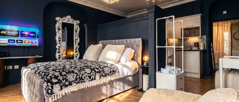 A modern bedroom with a large bed, a TV, a decorative mirror, and a built-in wardrobe.