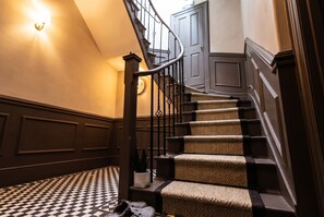Eine Treppe mit einem Schachbrettmuster, einer Wandleuchte und einer Tür am oberen Ende.
