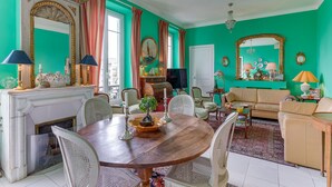 Een eetgedeelte met een ronde tafel, stoelen, een open haard en een bank in een kamer met turquoise wanden.