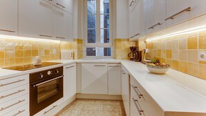 Een moderne keuken met witte kasten, een ingebouwde oven, een raam en een kom op het aanrecht.