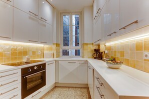 A modern kitchen with white cabinets, a built-in oven, a window, and a bowl on the counter. - GAMBETTA GARDEN AP4507 by Riviera Holiday Homes (Nice)