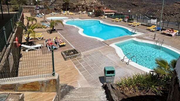 A pool area with multiple pools, lounge chairs, and a staircase leading down. - Vista Mar - Playa del cura (Mogán)