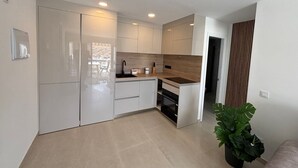 A modern kitchen with white cabinets, a wooden countertop, and a built-in oven. - Vista Mar - Playa del cura (Mogán)