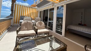 A sunlit outdoor seating area with striped awnings, wicker chairs, a glass table, and a sofa. - Vista Mar - Playa del cura (Mogán)