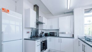 A modern kitchen with white cabinets, a microwave, a stove, and a sink. - Luxury 3 Bed - 6 min to Airport  (Cheadle)