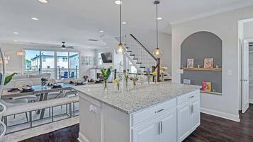 A spacious kitchen with a central island, pendant lighting, and a view to the outside.