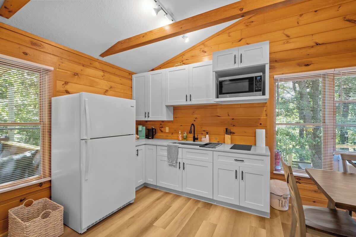 A compact kitchen with white cabinets, a microwave, and a refrigerator.